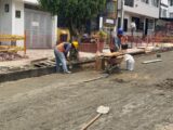 Obreros pavimentando una calle del barrio La Estrella de Manizales frente a locales comerciales